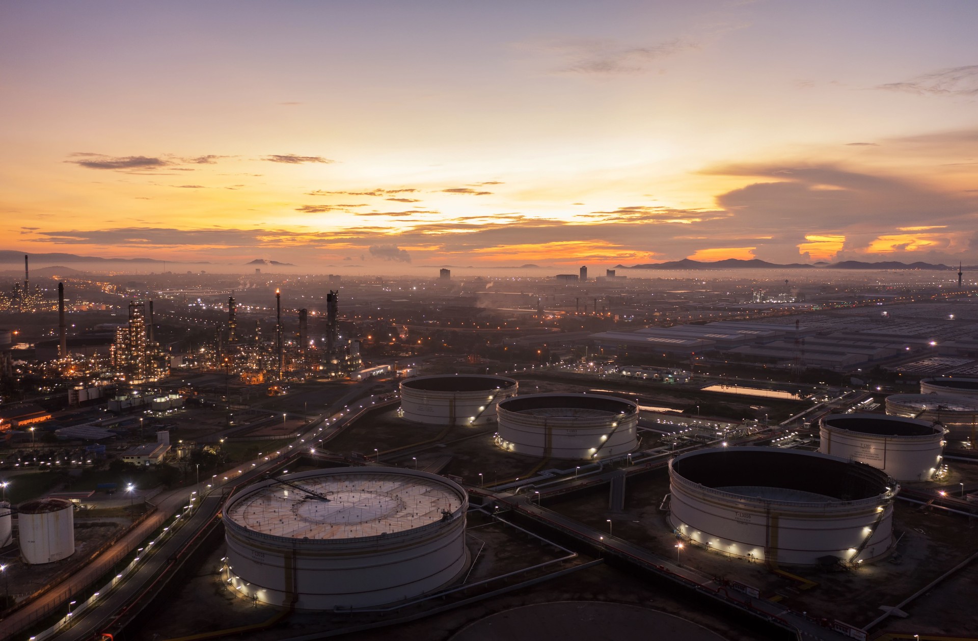 Aerial view drone of oil storage tank with oil refinery factory industrial. Oil refinery plant at beautiful sky sunset and twilight. industry factory concept and transportation.